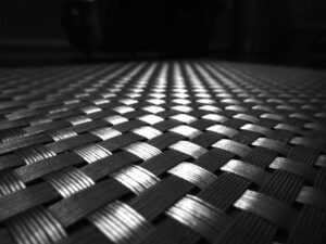 Close-up of a woven texture in black and white, showing light and shadow patterns.